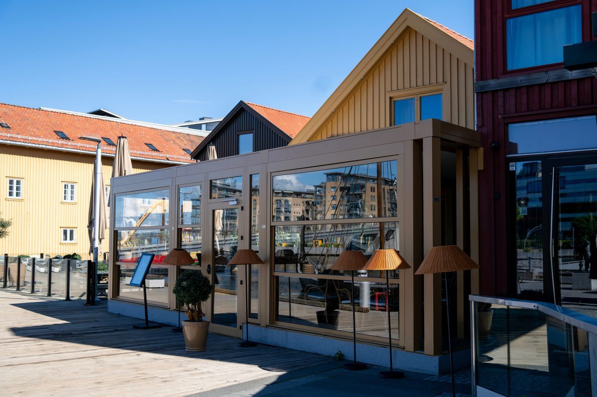 Innglasset uteservering med parapett-glassvinduer som kan kjøres opp og ned